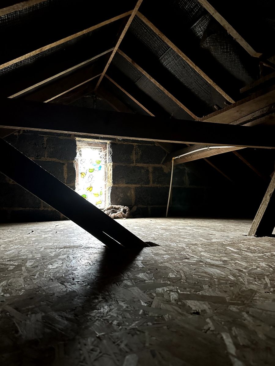 Large boarded loft with blockwork gable wall and a small window