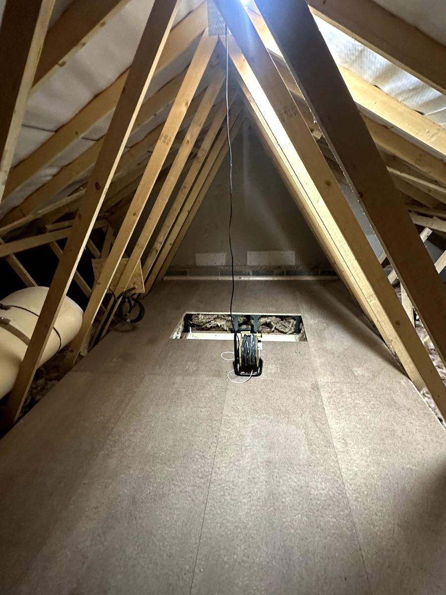 Finished boarded storage strip running the length of a modern trussed loft
